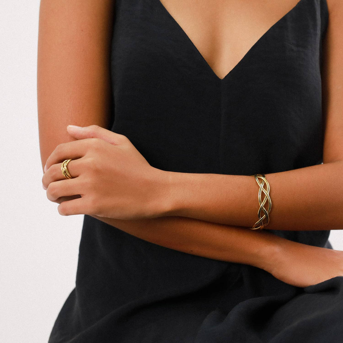 A person wearing a handmade gold Braided Cuff Bracelet on their wrist and a matching braided ring on their finger.