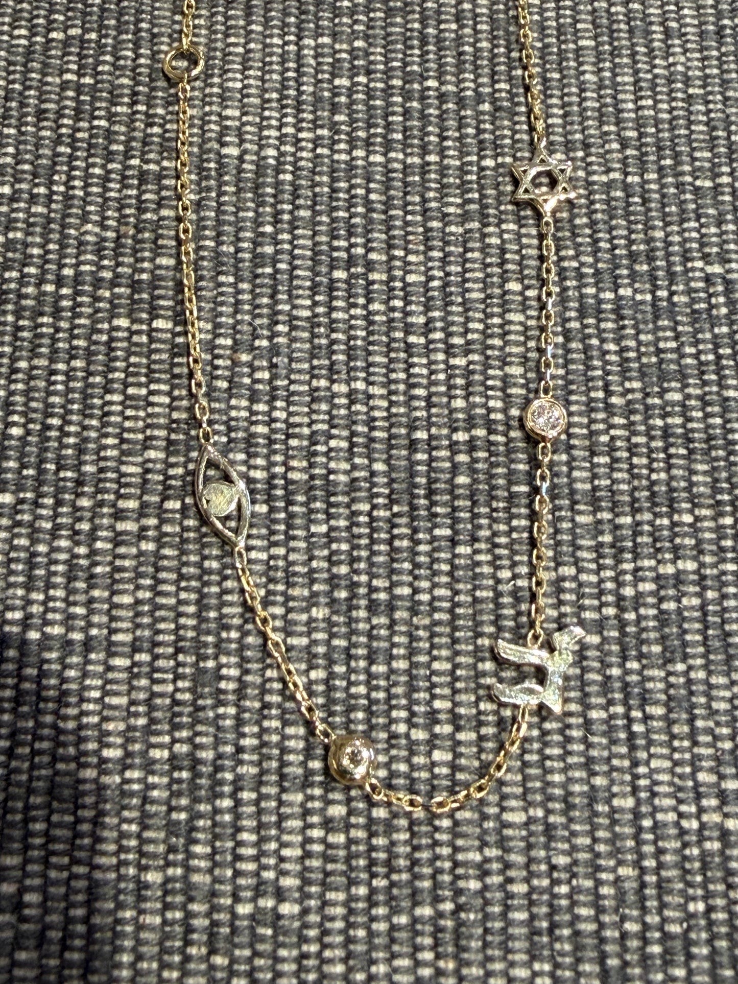 PK Fine 14k Solid Gold Judaic Symbols Bracelet featuring a Star of David, a hamsa, and a Hebrew letter charm, interspersed with small round charms.