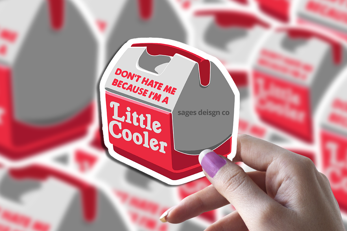 A hand holds Sticker Bull’s Little Cooler Sticker, a waterproof, scratch-resistant, and dishwasher-safe decal shaped like a red and white cooler featuring the phrase “DONT HATE ME BECAUSE IM A Little Cooler.” More identical stickers are softly blurred in the background.