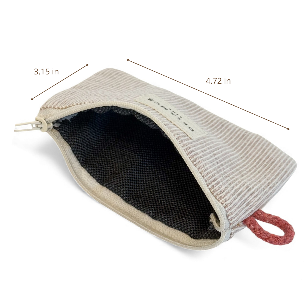 The Striped Coin Purse – Gray & Cream by DE LA MUR LINE US Inc is a small zippered purse crafted from jacquard fabric in Barcelona. Measuring 3.15 inches tall and 4.72 inches wide, it features a beige and gray striped design, a partially open zipper that reveals its black interior, and a red fabric loop attached to one corner for added convenience.
