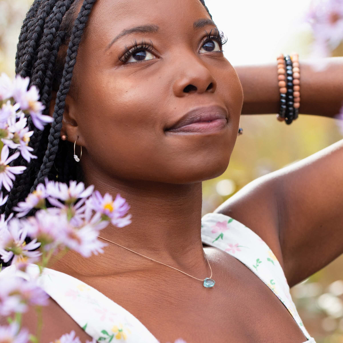 A person wearing a delicate, handmade SoulKu Powder Blue Crystal Necklace Gift for Breathe - Self Care featuring a single light blue pendant.