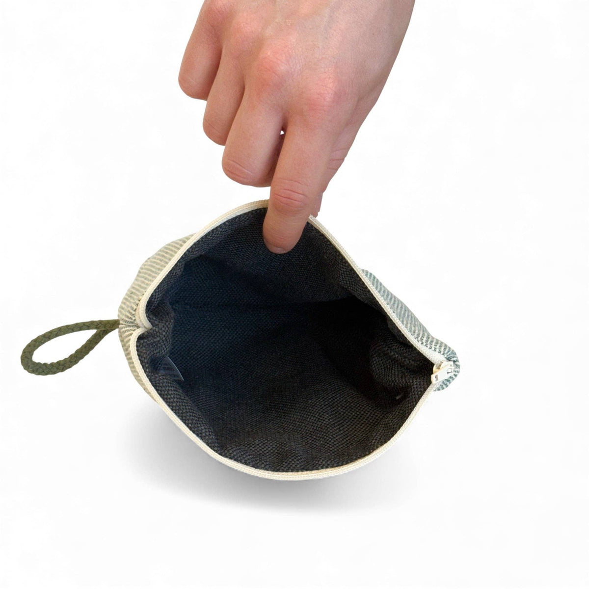 A hand holding open the Striped Small Makeup Bag – Light Green & Green (Teo) by DE LA MUR LINE US Inc, showing its empty interior and green drawstring against a white background.