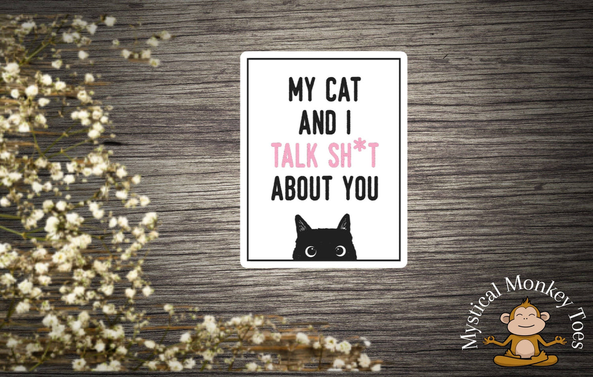 The My Cat And I Talk Sh*t About You Sticker by Mystical Monkey Toes features black cat eyes art, playful flowers, and a cartoon monkey logo in the corners.