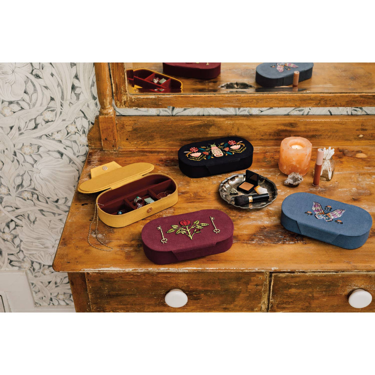 Oval Aurora Embroidered Jewelry Box - Blue/Pink containers with floral and embroidered butterfly designs displayed on a wooden vanity.