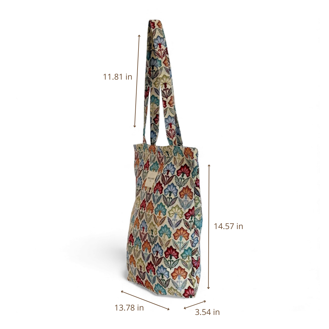 The Floral Jacquard Medium Zippered Tote Bag – Multicolor (Flora) by DE LA MUR LINE US Inc is displayed at an angle, featuring vibrant floral patterns on jacquard fabric. Dimensions are indicated as 11.81 in handle height, 14.57 in bag height, 13.78 in width, and 3.54 in depth, all shown against a white background.
