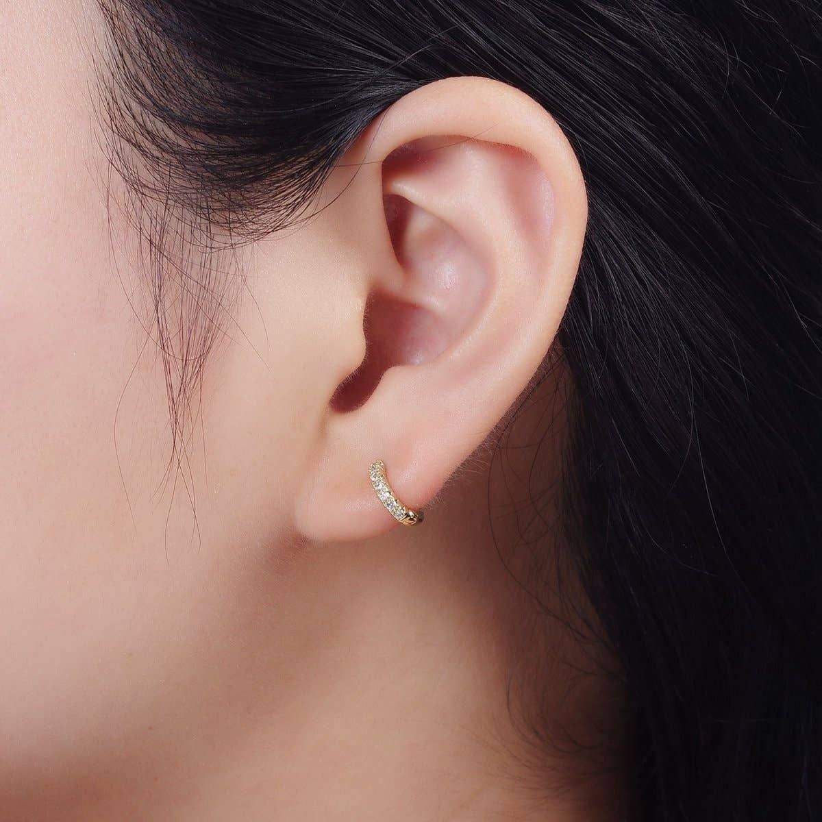 A 10mm Tiny CZ Clicker Hoops - Gold Filled earring with a row of pave CZ stones worn in an earlobe.
