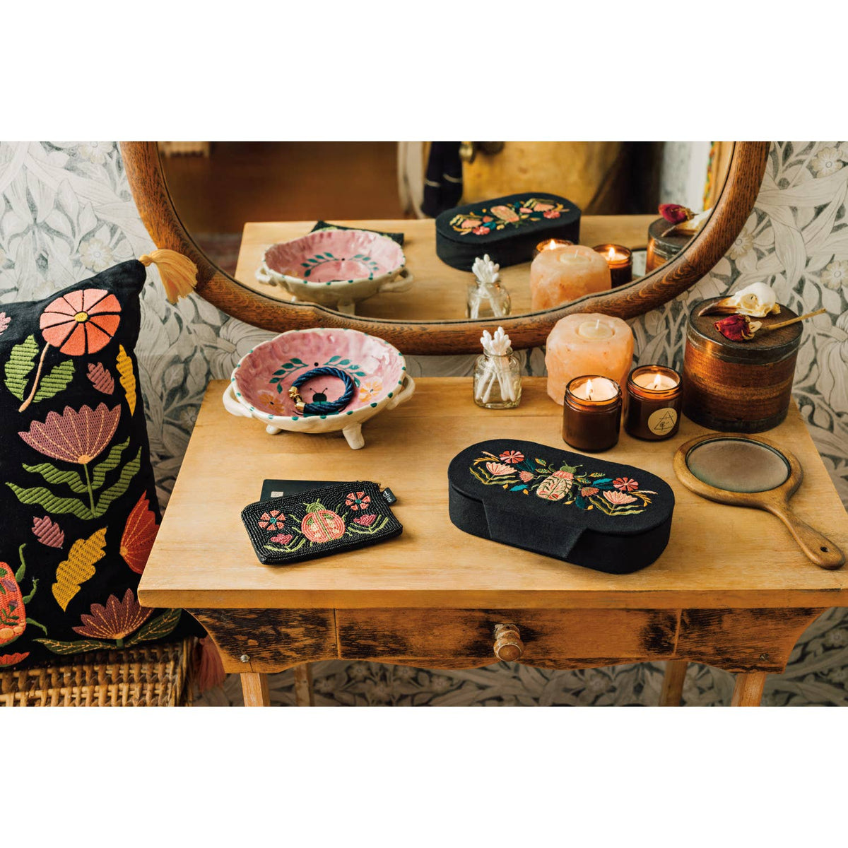 Black oval Amulet Embroidered Jewelry Box - Black/Pink with a beetle and floral motif, sitting on a wooden vanity next to a matching beaded card case.