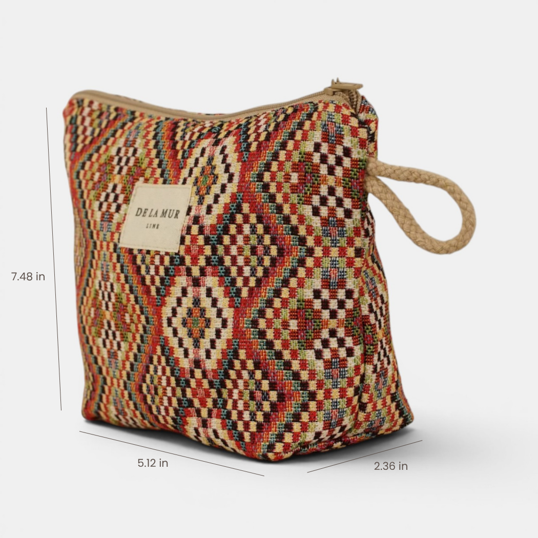 Introducing the Geometric Jacquard Small Makeup Bag – Red Multicolor (Otto) by DE LA MUR LINE US Inc: a square pouch crafted from jacquard fabric, featuring a vibrant geometric multicolor design. It is detailed with a tan zipper and rope loop for easy carrying. Measuring 7.48 inches tall, 5.12 inches wide, and 2.36 inches deep, this pouch is perfect as a stylish makeup bag. The label reads DE LA MUR LINEN.