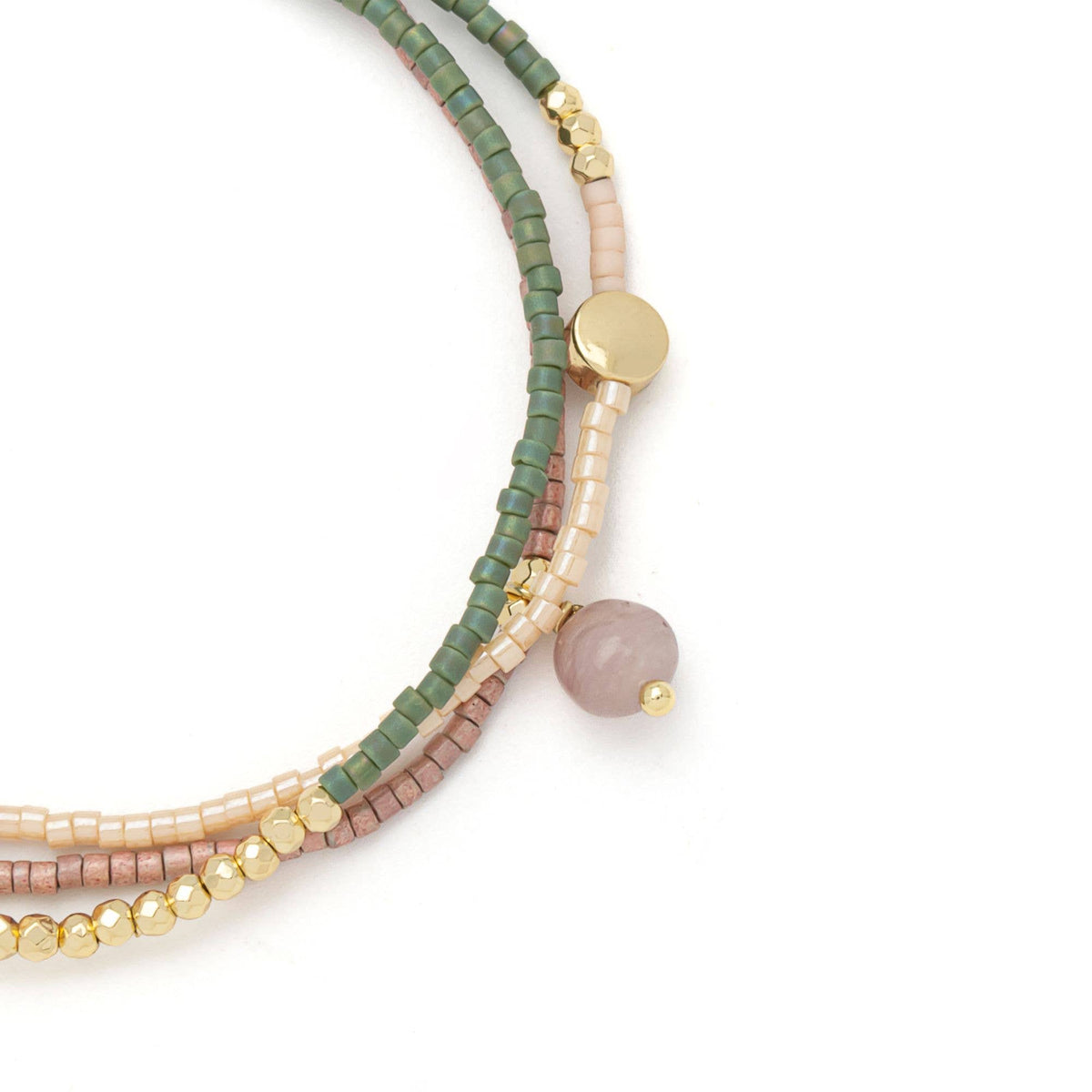 A close-up of the Scout Curated Wears Mixed Media Wrap Bracelet/Necklace - Healing/Tourmaline/Gold, showcasing green, blush pink, and gold beads intricately accented with Japanese Miyuki Beads, a single pink stone accent, and a round gold charm.