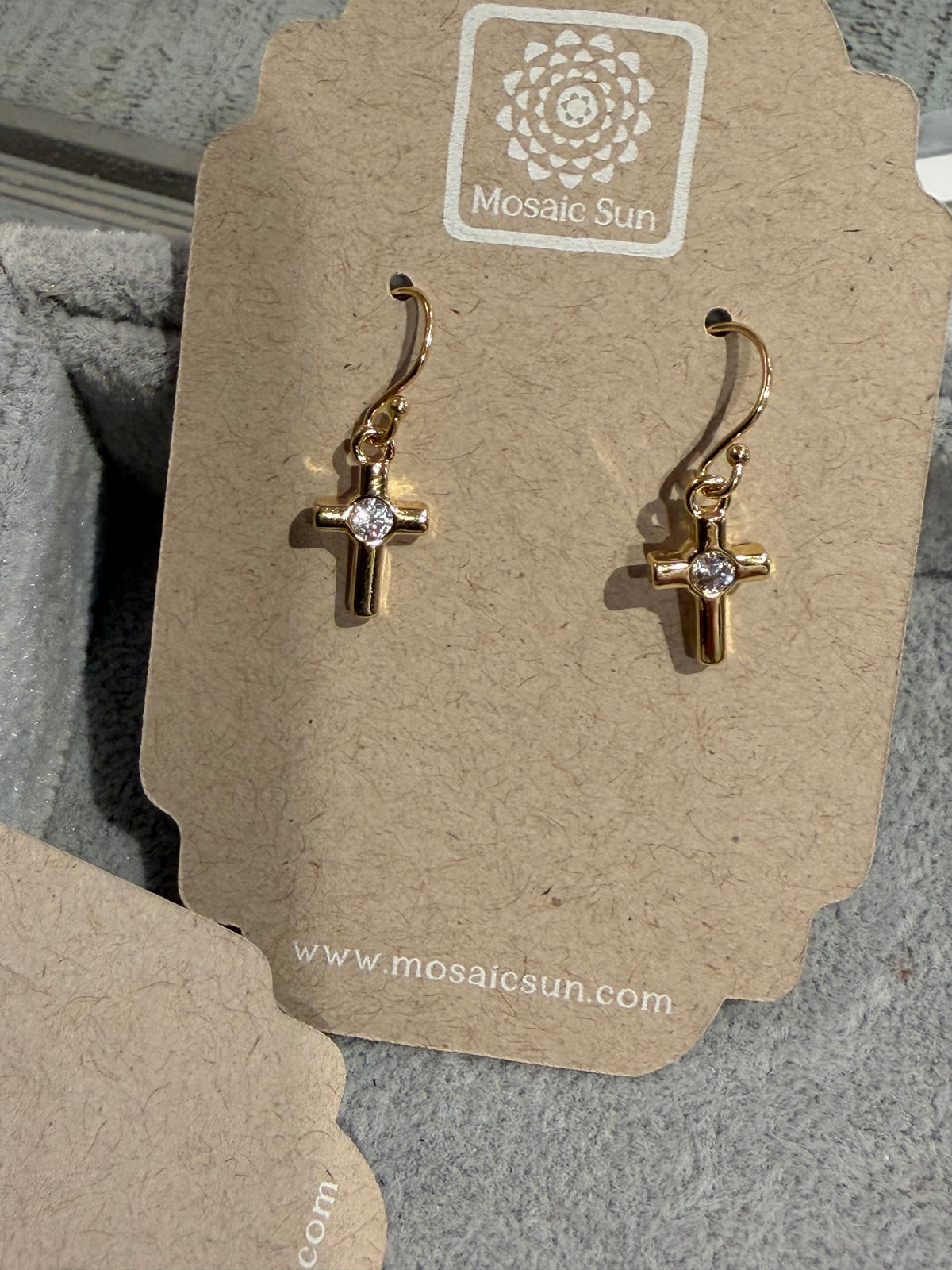 Sm CZ Cross Earrings - GF by GoldFi feature small clear gemstones at the center and are displayed on a brown Mosaic Sun card with the GoldFi name and logo above the earrings.