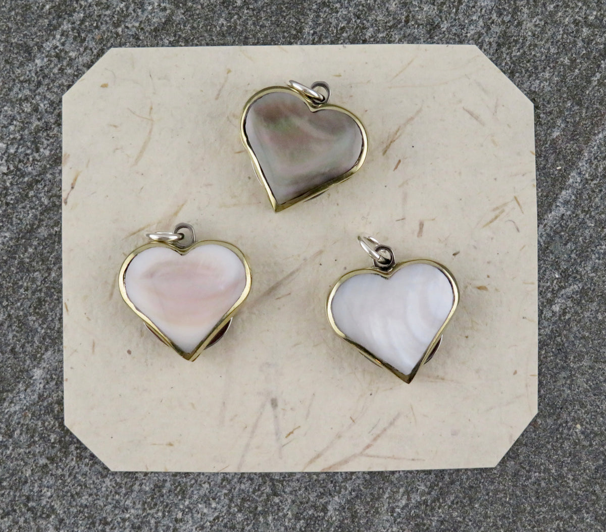 Three Mini Heart Knife Necklace pendant charms with metallic rims and iridescent abalone shell inlay.