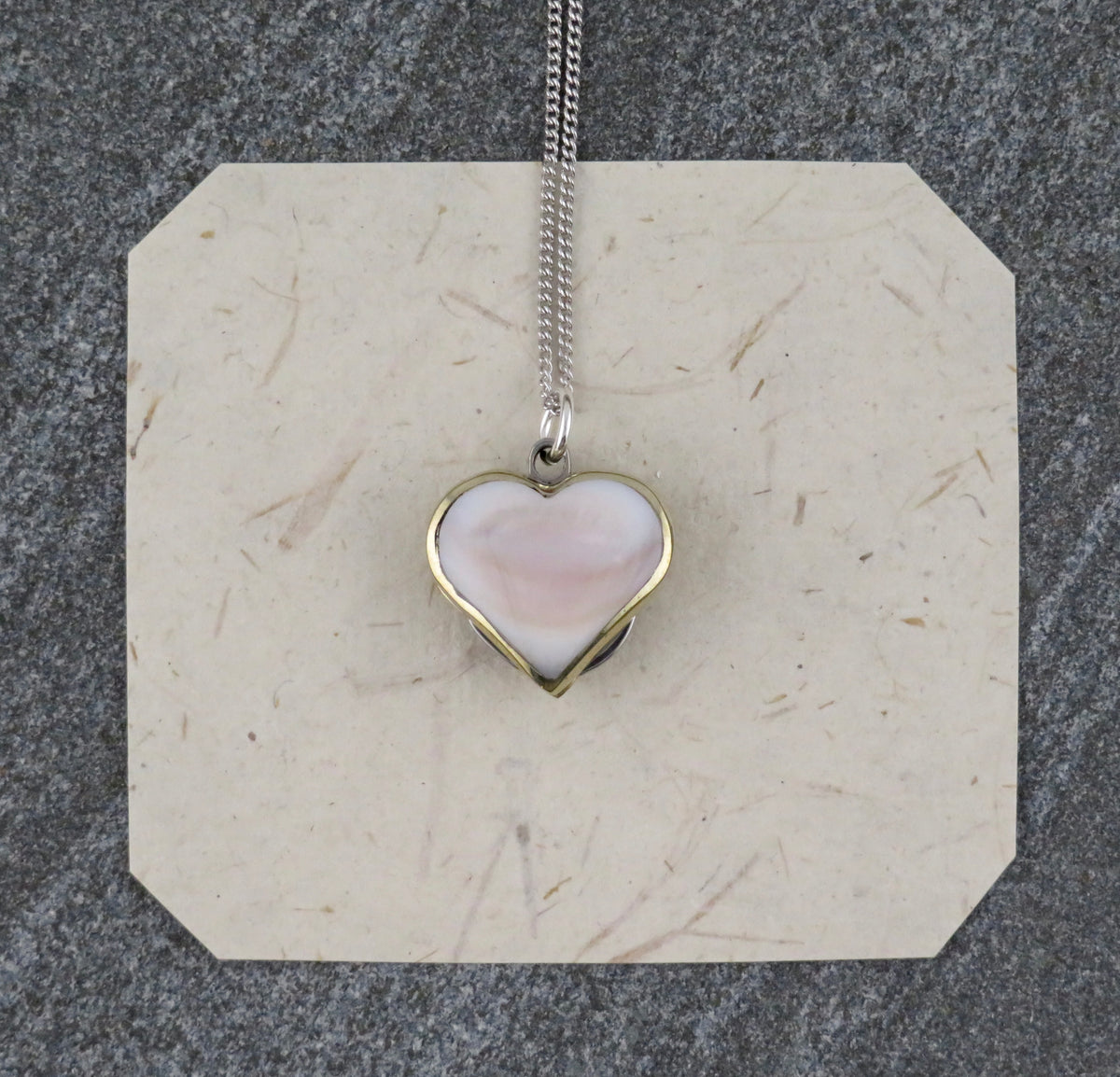 Mini Heart Knife necklace featuring a sterling silver curb chain and a heart-shaped pendant with a pale, polished abalone shell inlay.