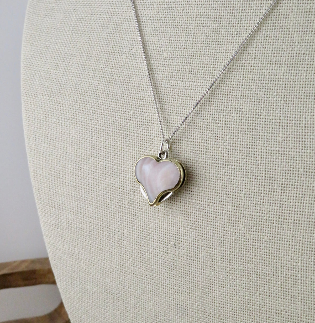 A Mini Heart Knife Necklace featuring a silver curb chain and a heart-shaped pendant with a light pink abalone shell inlay.