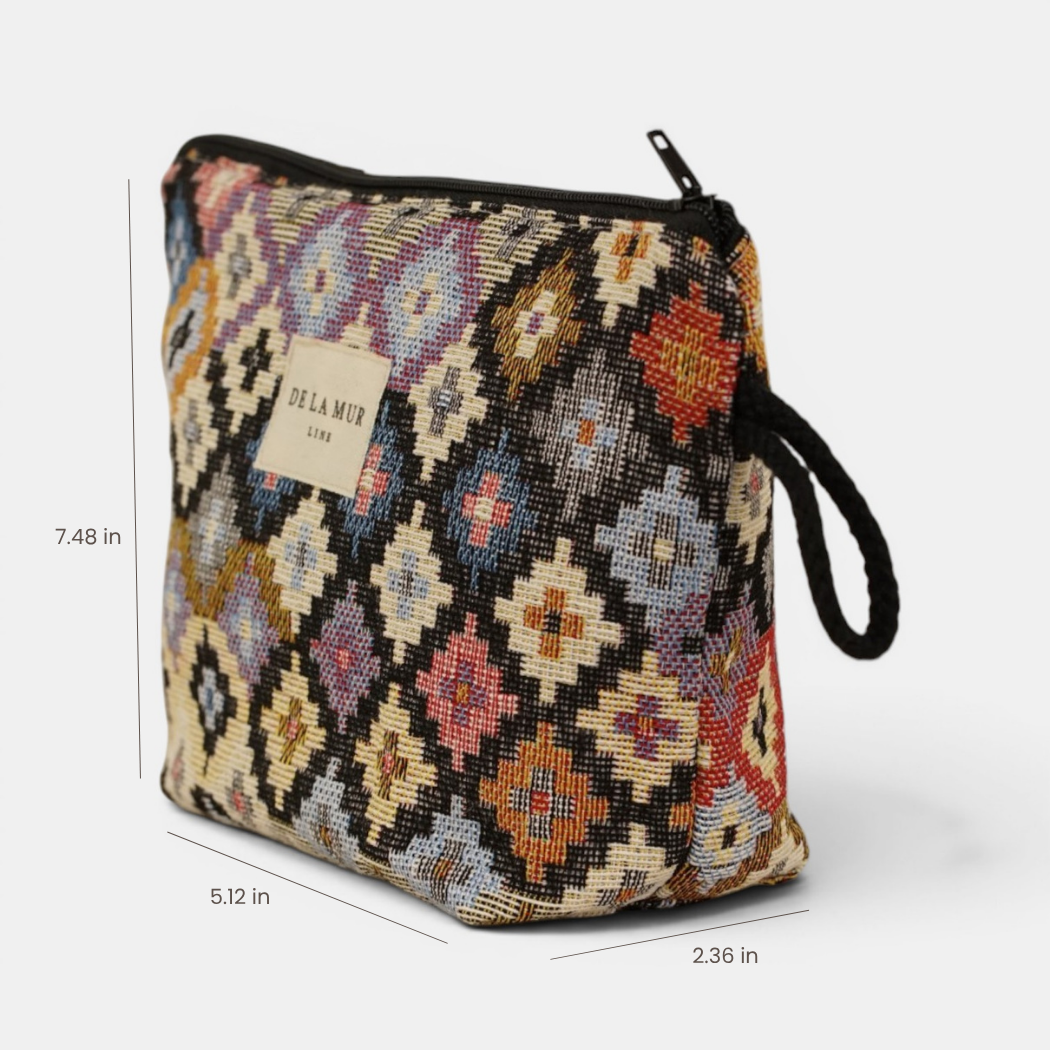 Introducing the Geometric Jacquard Small Makeup Bag – Multicolor (Ore) by DE LA MUR LINE US Inc. This pouch is crafted from patterned jacquard fabric, featuring vibrant geometric designs and a black handle. With a secure zipper closure, it measures 7.48 inches high, 5.12 inches wide, and 2.36 inches deep. Made in Barcelona, it’s perfect for organizing your makeup essentials on the go.