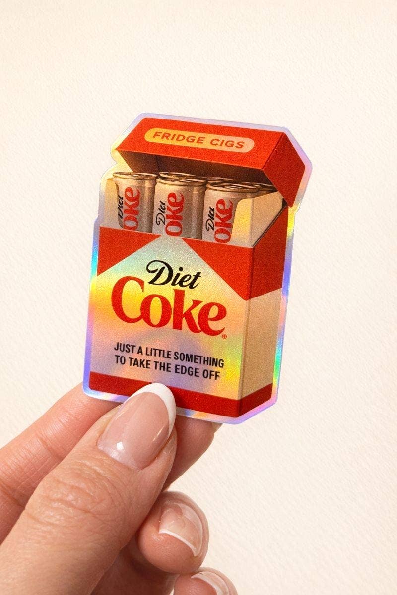 A hand holds the Diet Coke Fridge Cigs Sticker by Hello Brand | Sticker My Art, shaped like a retro cigarette pack with cans inside and “Just a little something to take the edge off”—durable and weather-resistant.