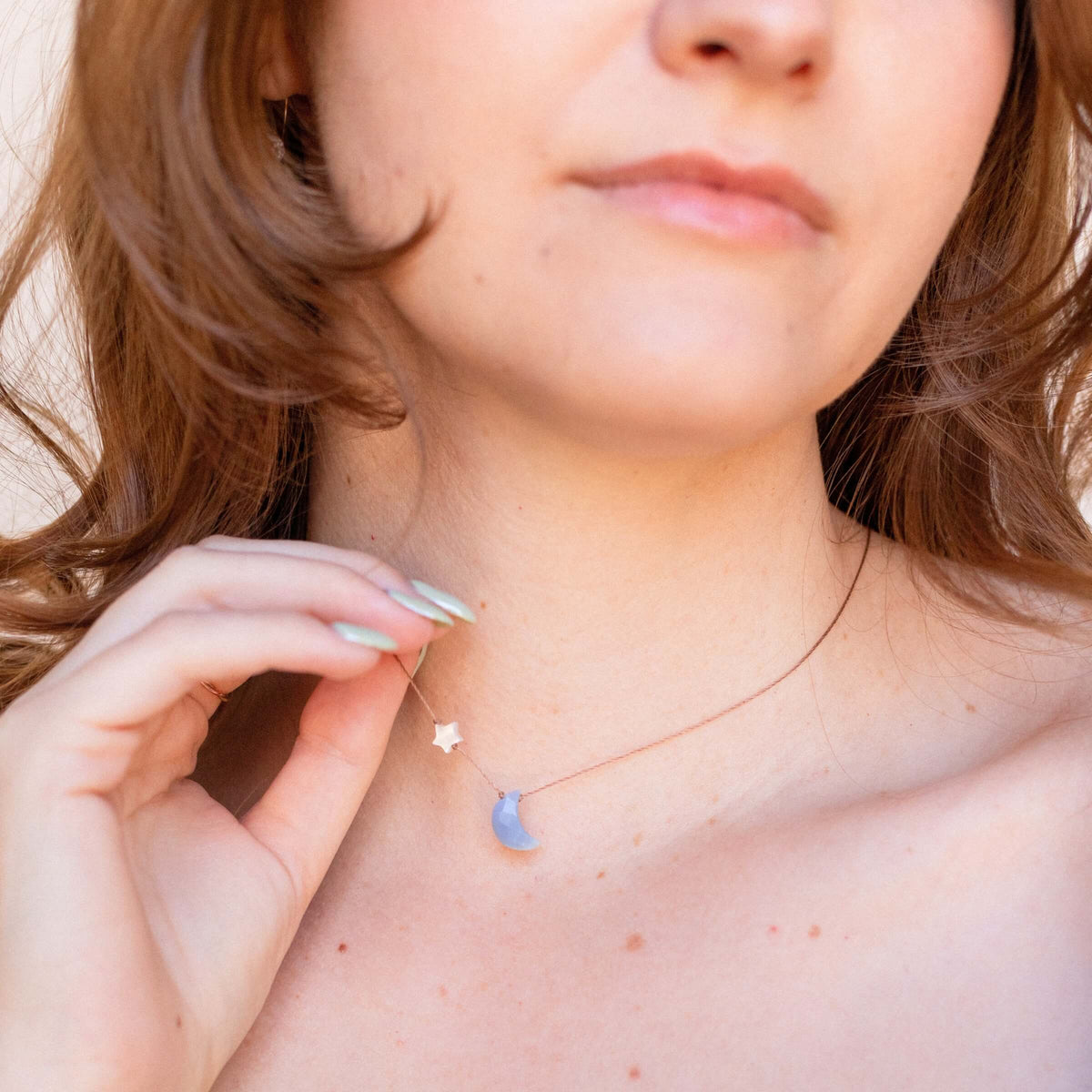 A person wearing a SoulKu Blue Opal - I Love You To The Moon & Back - Necklace featuring a thin chain with a small silver star charm and a light blue opal crescent moon pendant.