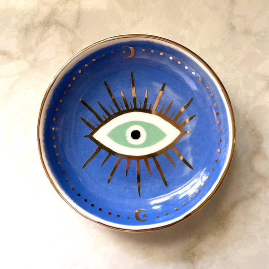 Round blue Porcelain Trinket Dish - Evil Eye featuring a central stylized eye and gold moon and star accents.