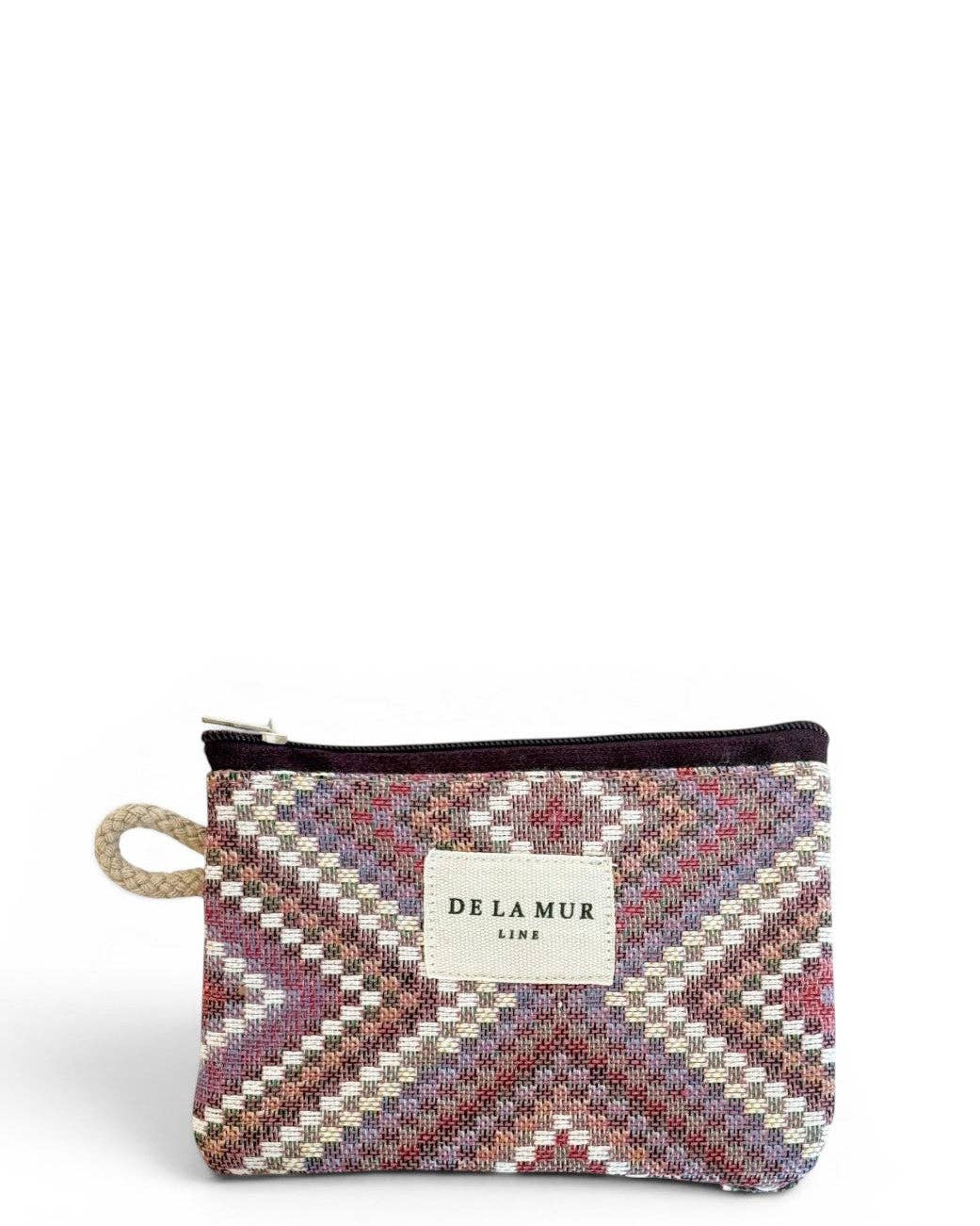Here is the revised sentence using the provided product data: The Geometric Jacquard Coin Purse – Pink & Lilac (Nana) from DE LA MUR LINE US Inc is a small coin purse crafted from jacquard fabric, showcasing a multicolored geometric kilim pattern, a top zipper closure, a rope loop on the left side, and a white label with “DE LA MUR LINE” displayed at the center.