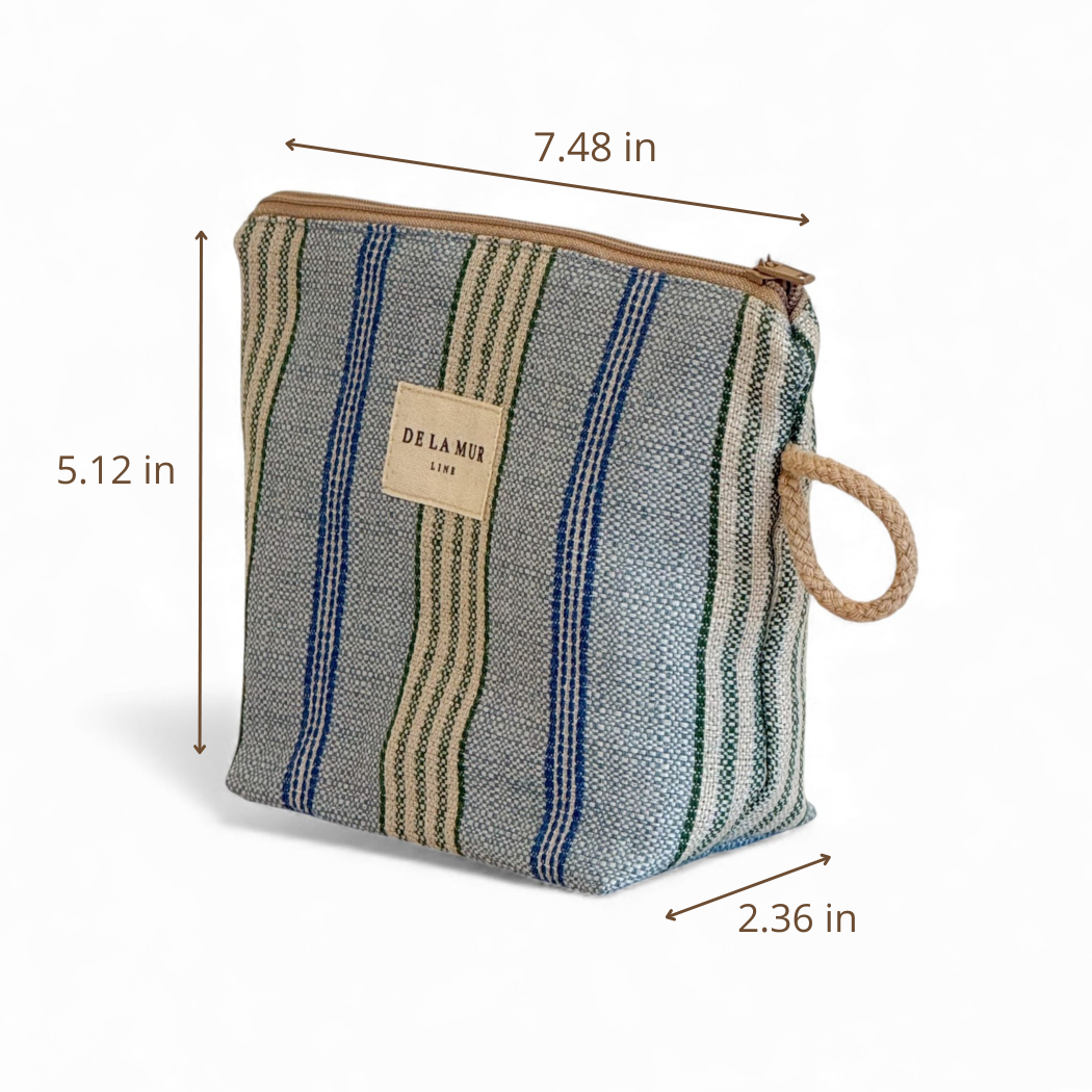 The Striped Jacquard Small Makeup Bag – Blue & Green (Cata) by DE LA MUR LINE US Inc features a striped jacquard fabric with a zipper closure, a rope handle, and is labeled with the brand’s name. Made in Barcelona, this compact makeup bag measures 7.48 inches wide, 5.12 inches high, and 2.36 inches deep.