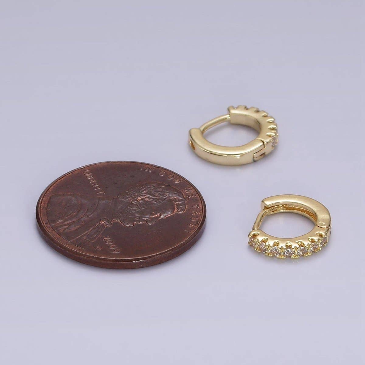 Two Tiny CZ Clicker Hoops - Gold Filled 10mm earrings studded with pave stones, positioned next to a copper penny for scale.