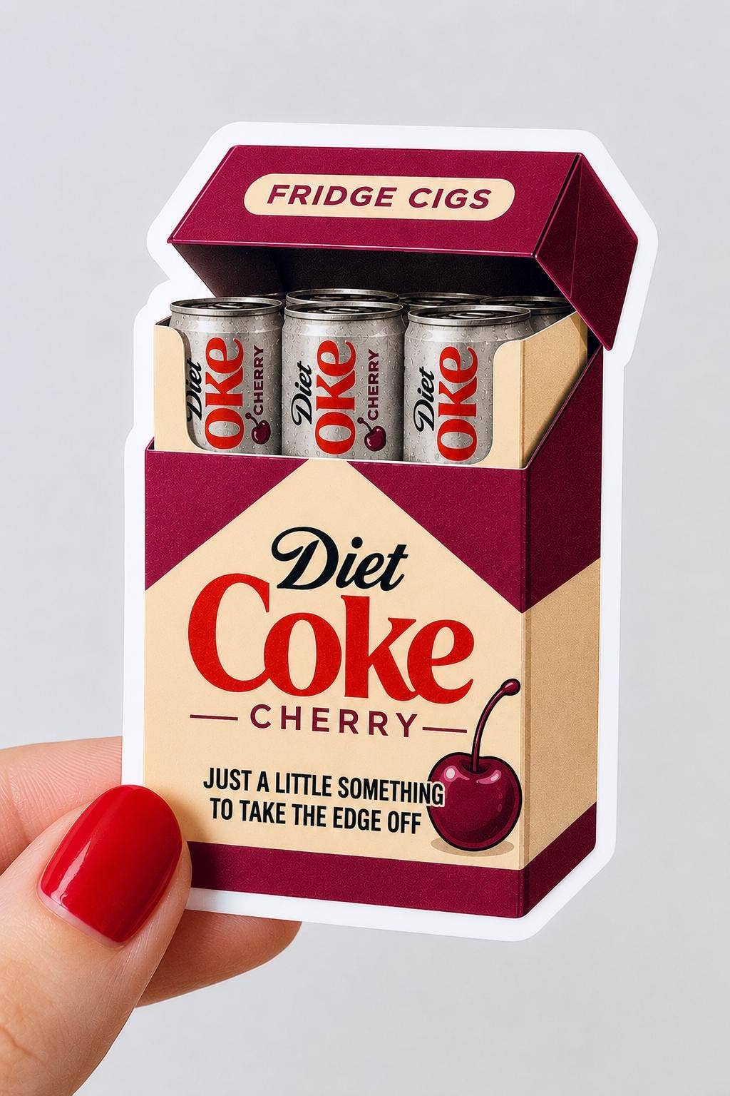 A hand holds the Diet Coke Fridge Cigs Sticker by Hello Brand | Sticker My Art, featuring a weather-resistant design like a cigarette pack, labeled Diet Coke Cherry with mini cans and cherry details.