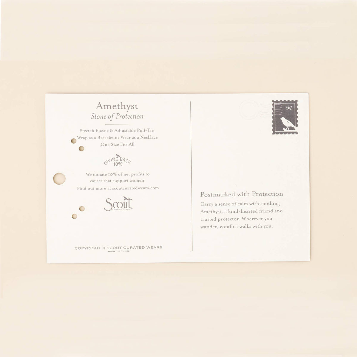 A cream-colored postcard featuring a description of amethyst as the Stone of Protection, the Scout Curated Wears logo, a black stamp, and small gold dots rests on a light surface—perfect for pairing with the Mixed Media Wrap Bracelet/Necklace – Protection/Amethyst/Gold from Scout Curated Wears, or other adjustable jewelry adorned with delicate Miyuki beads.