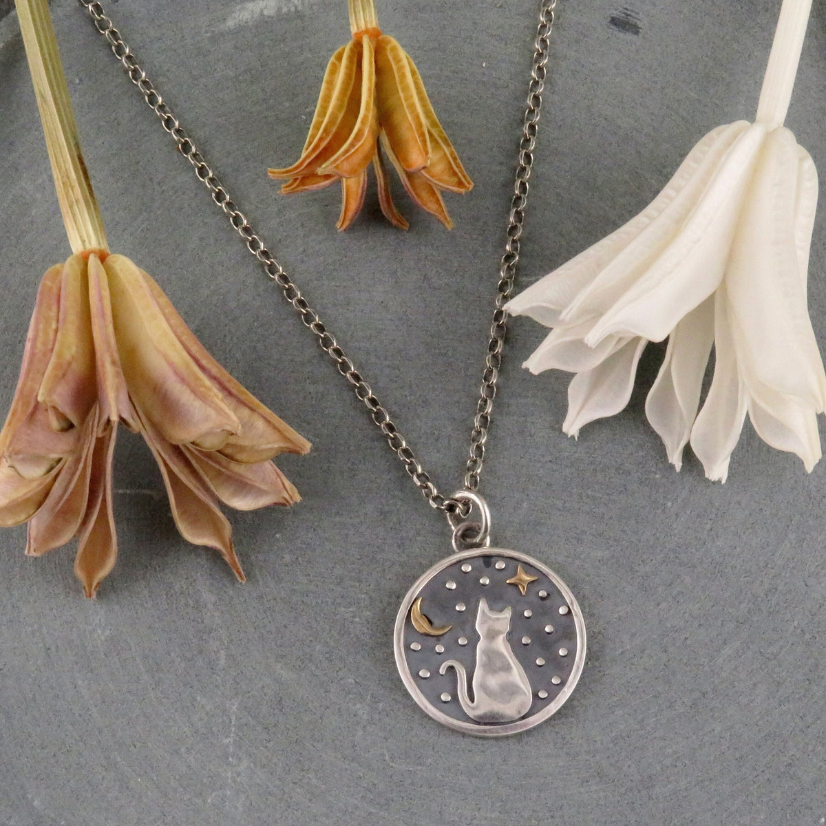 The Celestial Sitting Cat Necklace - Sterling by Nina Designs features a round sterling silver medallion pendant delicately depicting a cat, stars, and a crescent moon.